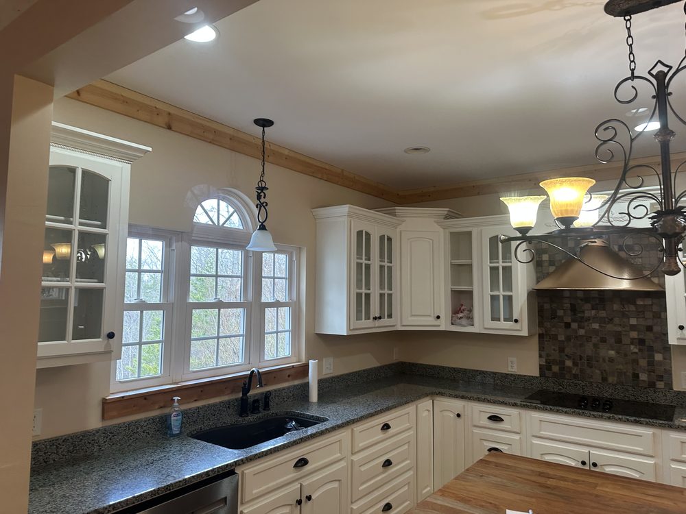 Refinished kitchen with cream-painted cabinets, glass-front uppers, and granite counters