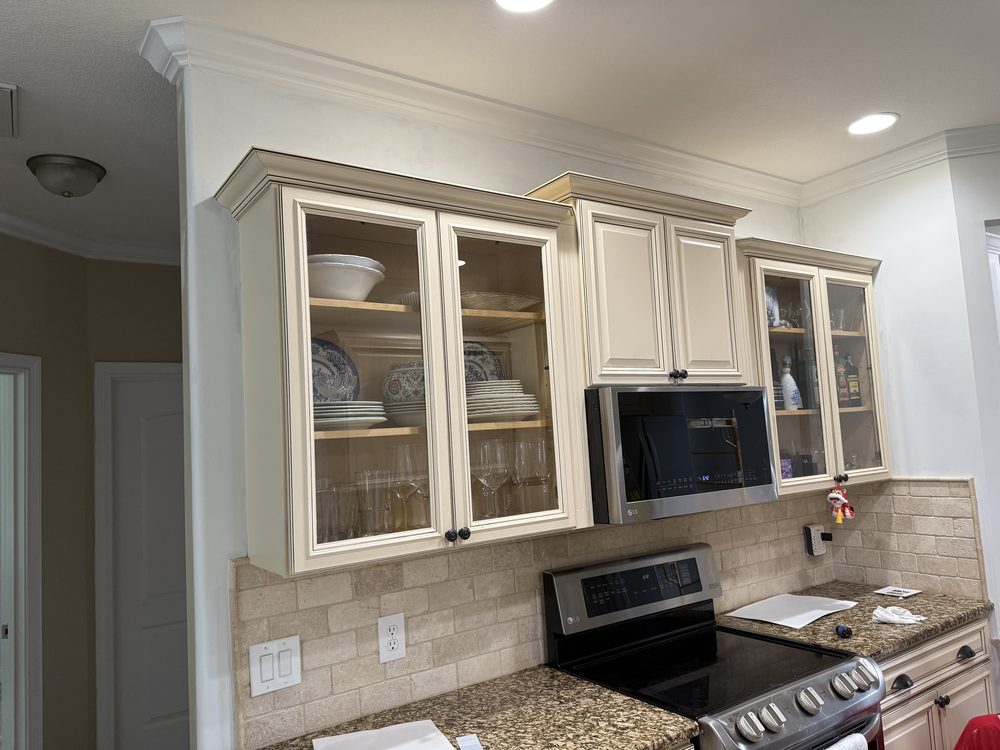 Antique-white refinished kitchen cabinets with a glazed finish and glass doors