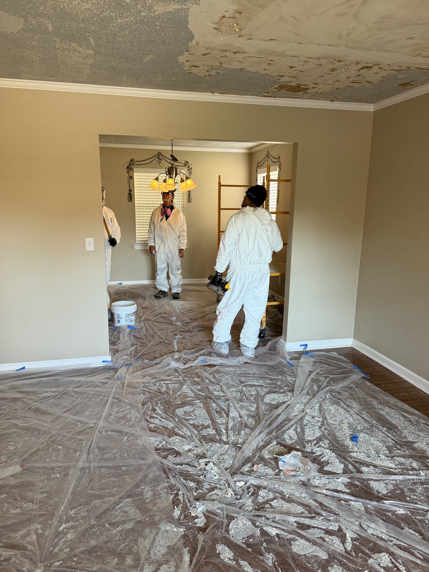 Crew in full PPE prepping a ceiling for paint